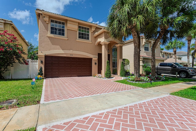 mediterranean / spanish house featuring stucco siding, decorative driveway, a garage, and a gate