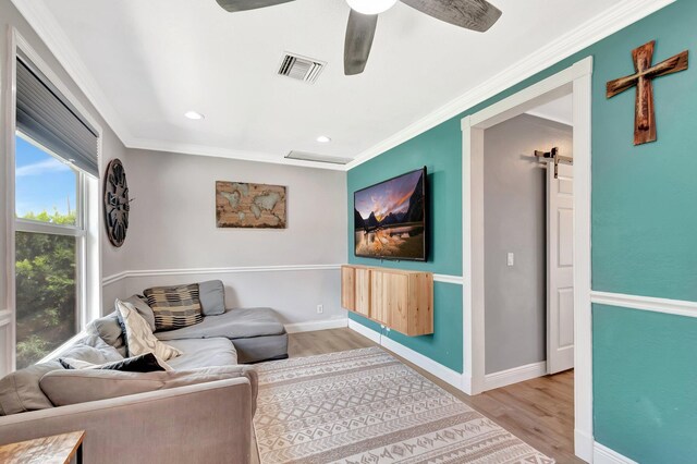 850 Green St, West Palm Beach, FL 33405 - living area featuring a barn door, a ceiling fan, wood finished floors, visible vents, and ornamental molding