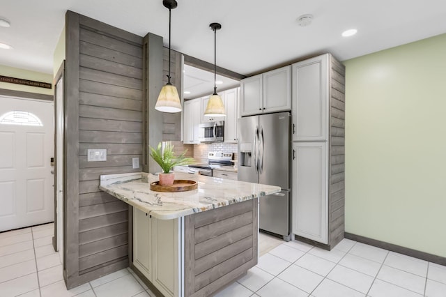 1116 Lake Ter Unit 203, Boynton Beach, FL 33426 - kitchen featuring appliances with stainless steel finishes, light stone counters, light tile patterned floors, decorative backsplash, and hanging light fixtures