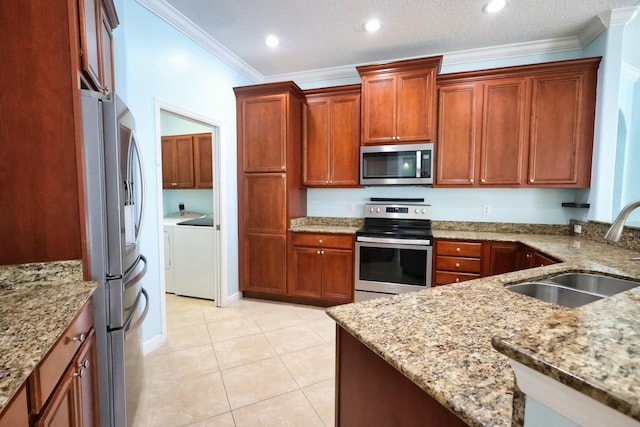 kitchen with stainless steel appliances, a sink, independent washer and dryer, light stone countertops, and light tile patterned flooring