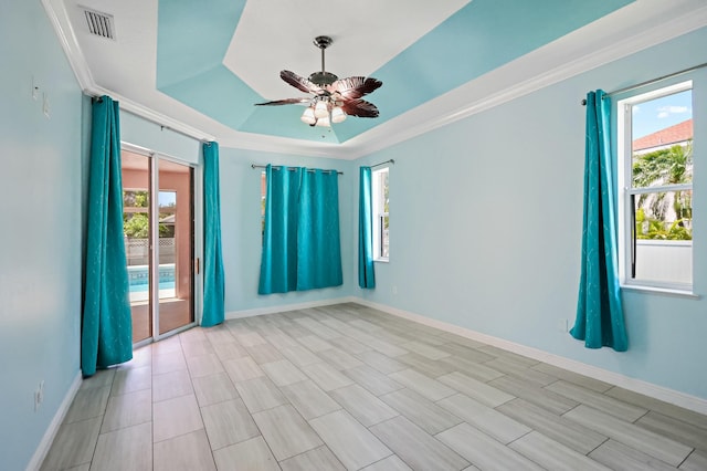empty room with ceiling fan, baseboards, a tray ceiling, and ornamental molding