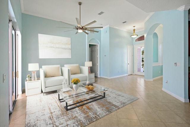 living area with arched walkways, ornamental molding, light tile patterned flooring, a ceiling fan, and baseboards