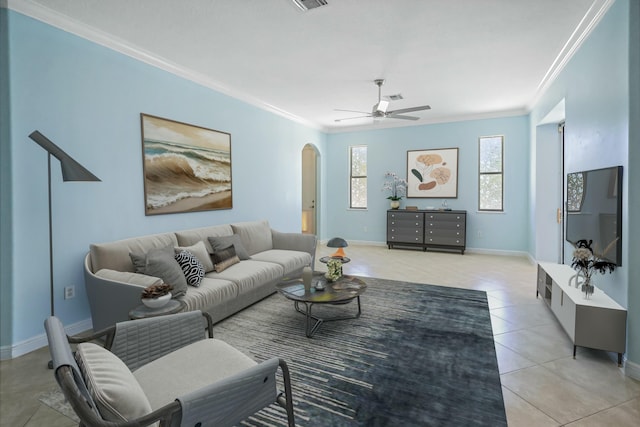 living room featuring arched walkways, crown molding, light tile patterned flooring, ceiling fan, and baseboards