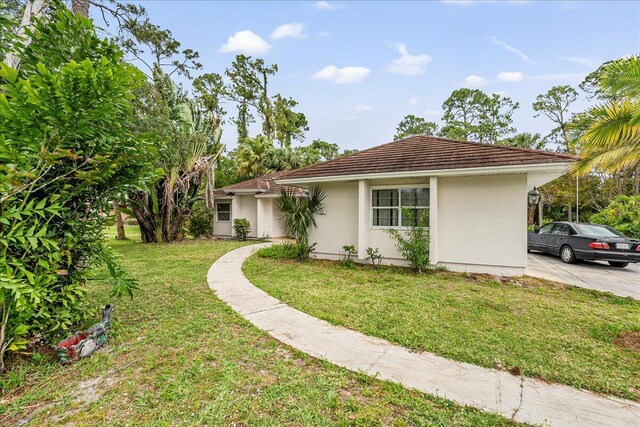 view of side of home featuring stucco siding, a tile roof, and a yard