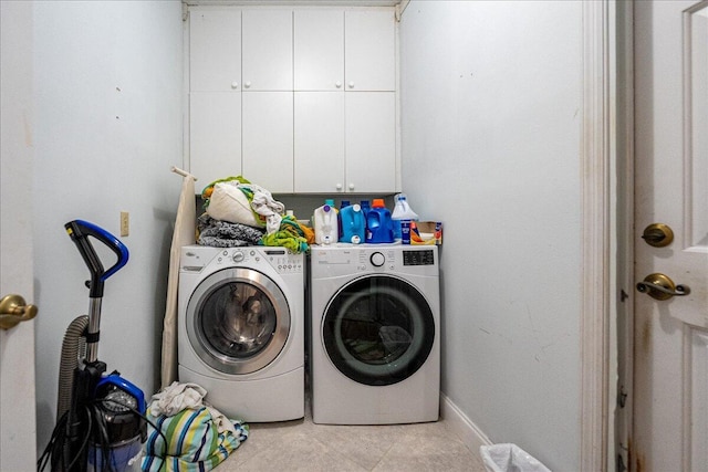 clothes washing area with separate washer and dryer, baseboards, light tile patterned floors, and cabinet space