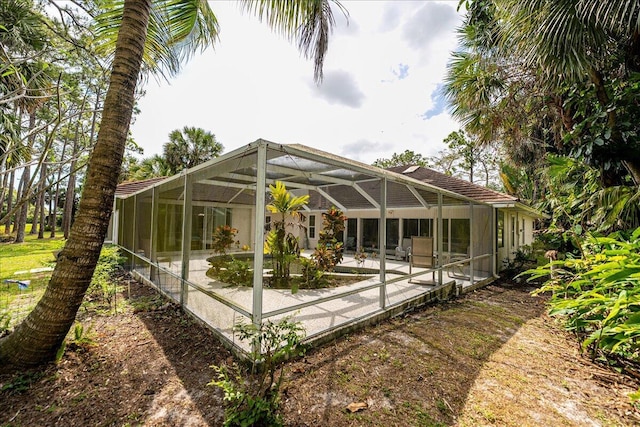 rear view of property with a patio area and glass enclosure