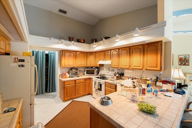 kitchen with tile counters, light tile patterned flooring, white appliances, under cabinet range hood, and visible vents
