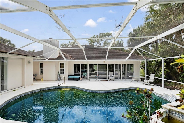 outdoor pool featuring glass enclosure and a patio