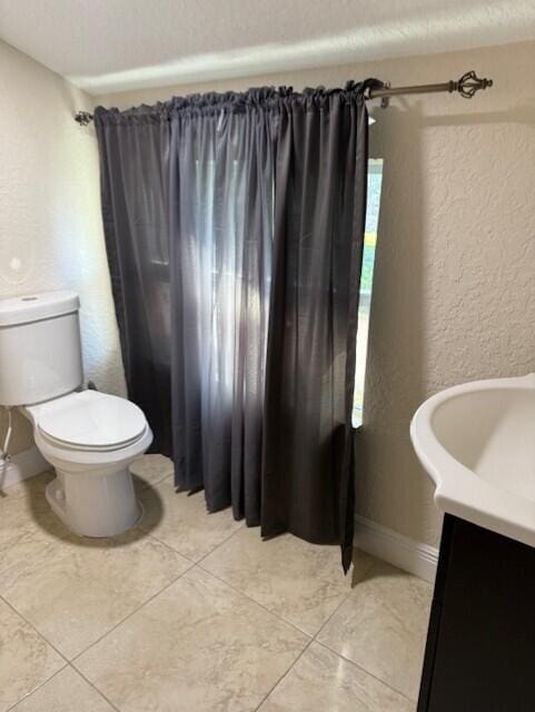 795 SW All American Blvd, Palm City, FL 34990 - bathroom with baseboards, toilet, a textured wall, vanity, and tile patterned floors