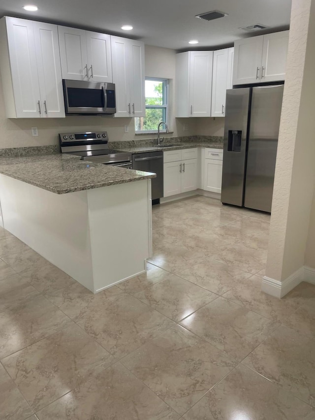 795 SW All American Blvd, Palm City, FL 34990 - kitchen with dark stone countertops, a peninsula, white cabinets, visible vents, and appliances with stainless steel finishes