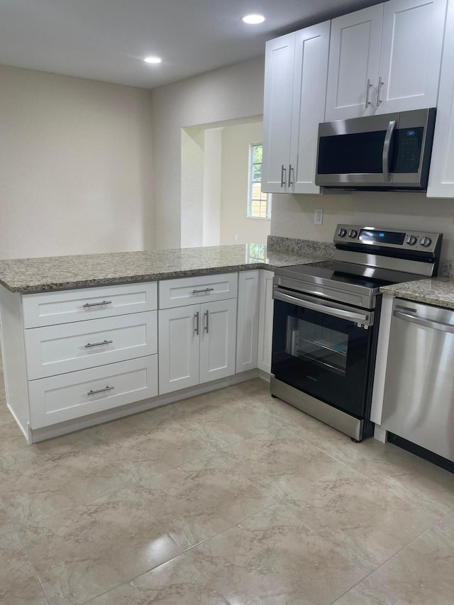 795 SW All American Blvd, Palm City, FL 34990 - kitchen with a peninsula, light stone counters, white cabinets, and stainless steel appliances