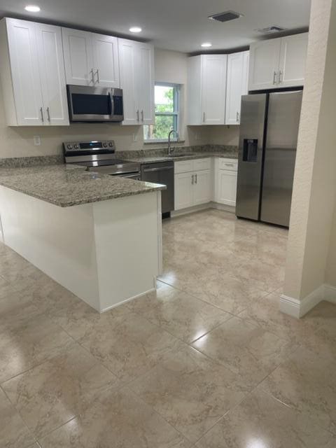 795 SW All American Blvd, Palm City, FL 34990 - kitchen with white cabinetry, visible vents, appliances with stainless steel finishes, and a peninsula