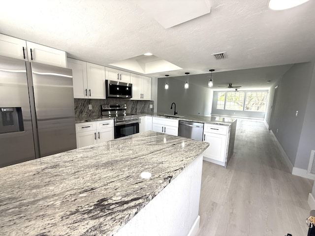 208 Palm Beach Trace Dr, Royal Palm Beach, FL 33411 - kitchen with stainless steel appliances, a peninsula, a sink, white cabinetry, and decorative backsplash