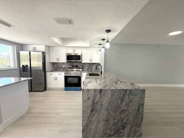 208 Palm Beach Trace Dr, Royal Palm Beach, FL 33411 - kitchen featuring stainless steel appliances, a sink, a peninsula, light wood-style flooring, and a textured ceiling