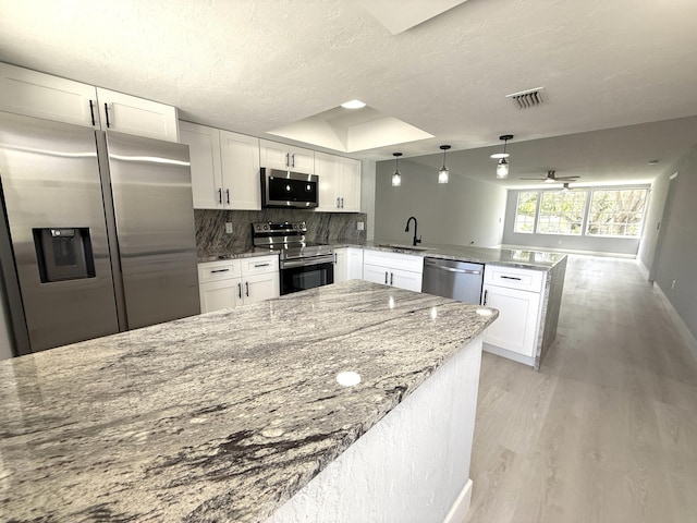 208 Palm Beach Trace Dr, Royal Palm Beach, FL 33411 - kitchen featuring stainless steel appliances, a peninsula, white cabinetry, light wood-style flooring, and backsplash