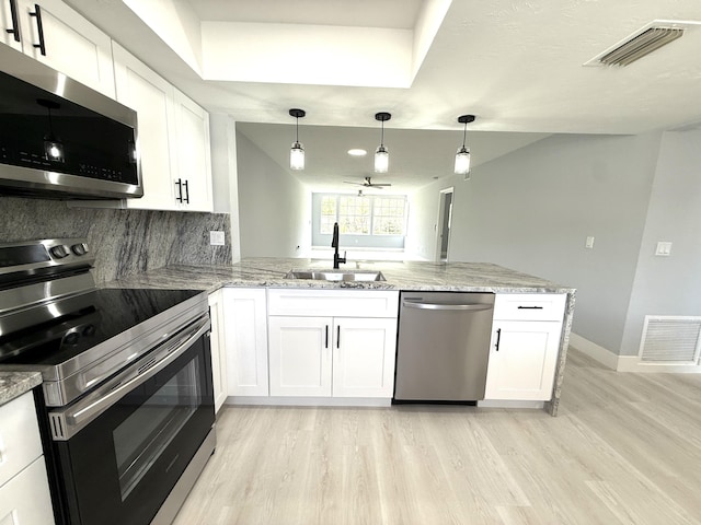 208 Palm Beach Trace Dr, Royal Palm Beach, FL 33411 - kitchen featuring stainless steel appliances, a sink, light wood finished floors, a peninsula, and white cabinets
