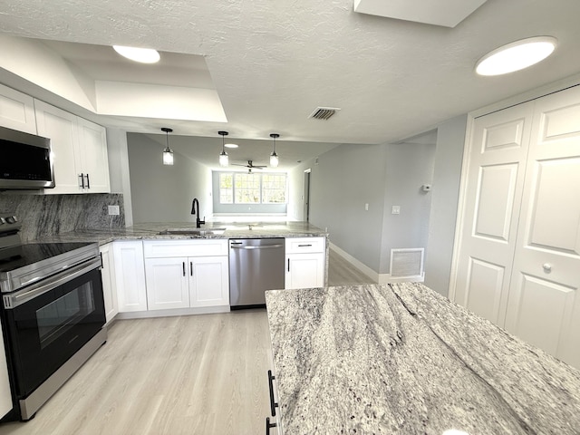 208 Palm Beach Trace Dr, Royal Palm Beach, FL 33411 - kitchen with appliances with stainless steel finishes, a sink, light wood-style floors, a peninsula, and white cabinetry