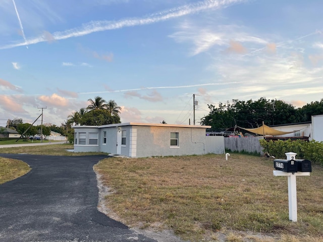 manufactured / mobile home with fence, aphalt driveway, stucco siding, and a front yard