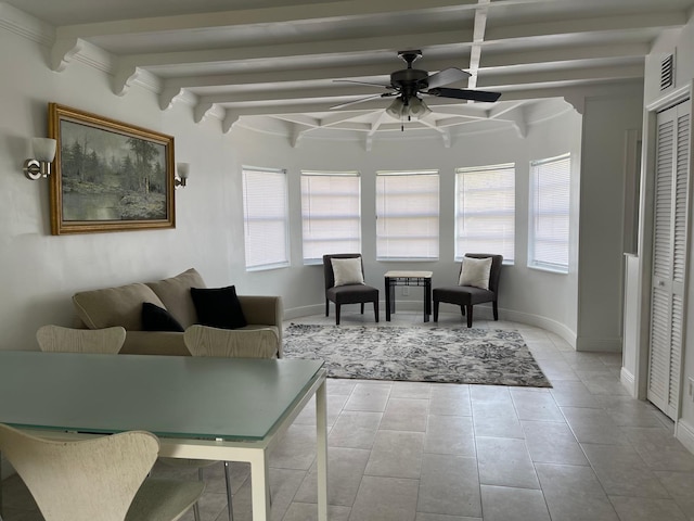 tiled living area with plenty of natural light, beamed ceiling, a ceiling fan, and baseboards