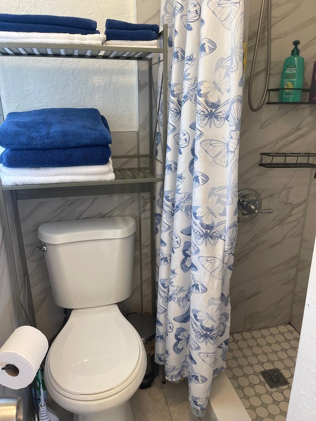 bathroom with toilet, a shower stall, and tile patterned floors