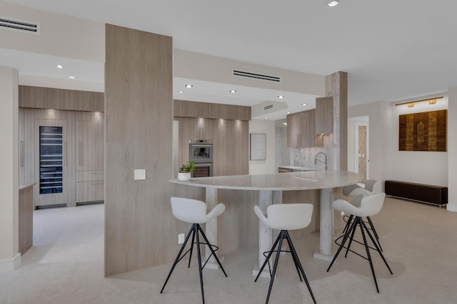 7351 Promenade Dr Unit 801F, Boca Raton, FL 33433 - kitchen with modern cabinets, double oven, a kitchen bar, a peninsula, and light countertops
