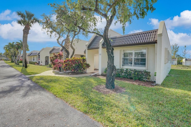 single story home with stucco siding, a tile roof, and a front yard