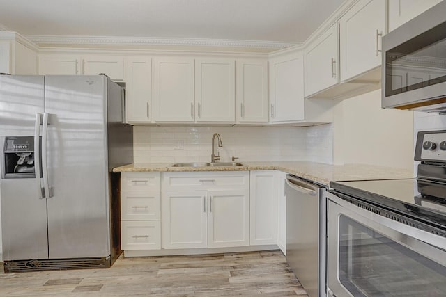 kitchen featuring light wood-style flooring, a sink, tasteful backsplash, light stone counters, and appliances with stainless steel finishes