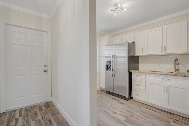 kitchen with light wood-style floors, stainless steel refrigerator with ice dispenser, and ornamental molding