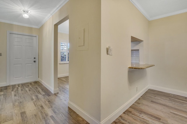entrance foyer featuring wood finished floors, crown molding, and baseboards