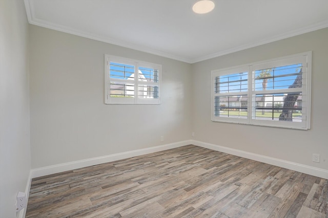 spare room with wood finished floors, a wealth of natural light, and ornamental molding