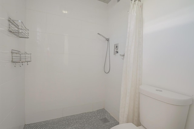 bathroom with a tile shower and toilet