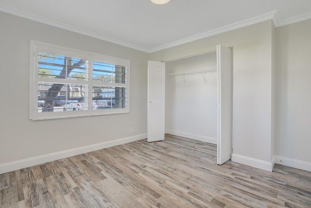unfurnished bedroom with baseboards, ornamental molding, wood finished floors, and a closet