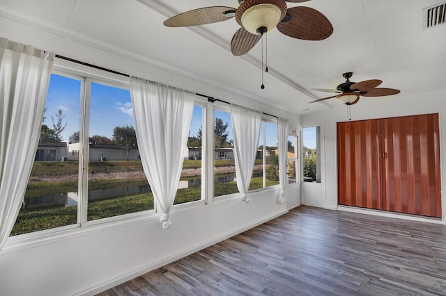 unfurnished sunroom with a healthy amount of sunlight, wood finished floors, visible vents, and a water view