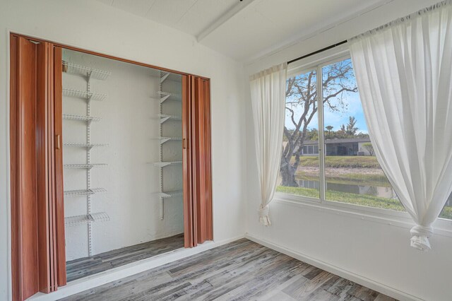 spare room featuring wood finished floors, a water view, and baseboards