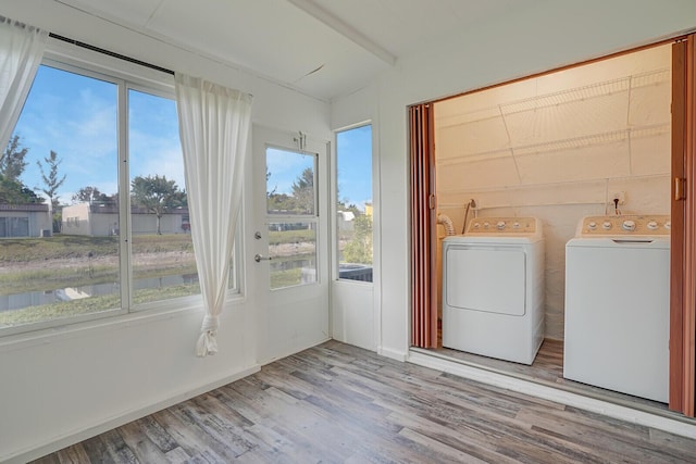 laundry room with separate washer and dryer, wood finished floors, laundry area, and a water view