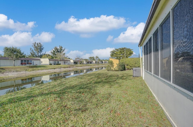 view of yard with a residential view, central AC, and a water view