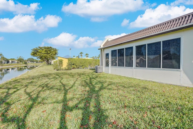 view of yard with cooling unit, a sunroom, and a water view