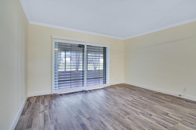 spare room with baseboards, wood finished floors, and crown molding