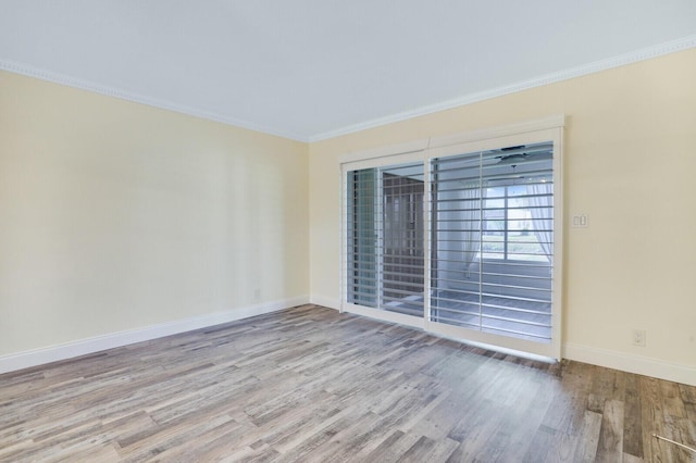 spare room featuring baseboards, crown molding, and wood finished floors