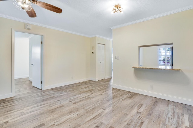 spare room with crown molding, a ceiling fan, baseboards, and light wood-style flooring