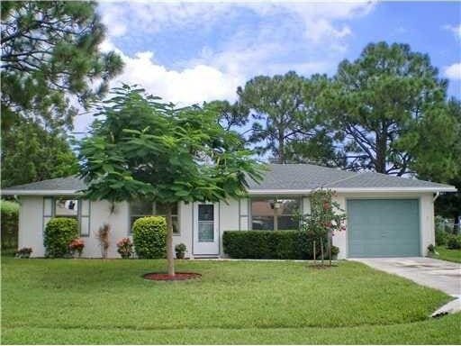 view of front of home with concrete driveway, stucco siding, an attached garage, and a front lawn