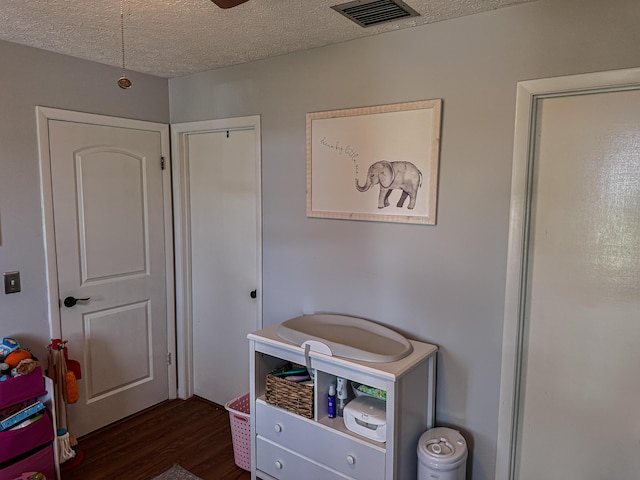 bedroom featuring visible vents, a textured ceiling, and dark wood finished floors