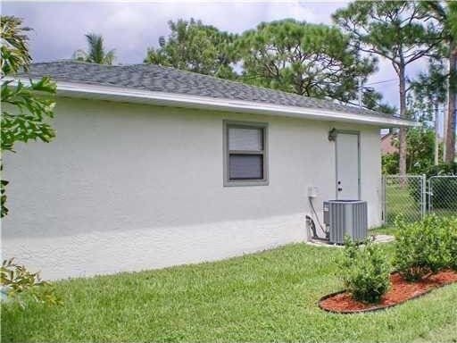 back of property with roof with shingles, central air condition unit, stucco siding, and fence