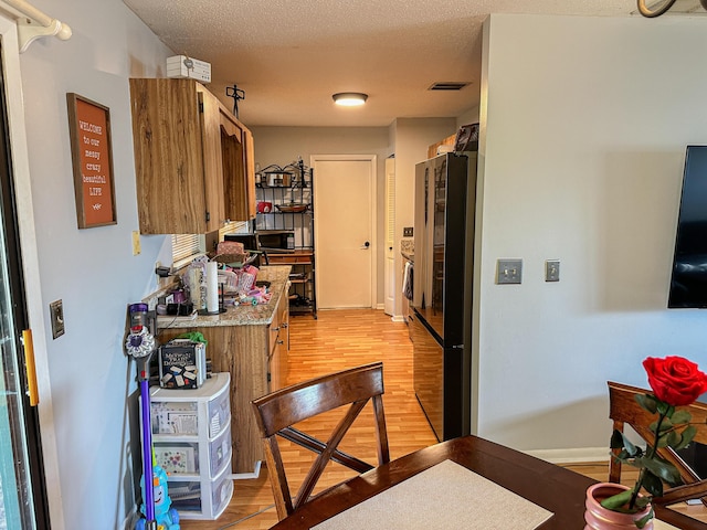 kitchen featuring light wood-style floors, visible vents, light countertops, and black appliances