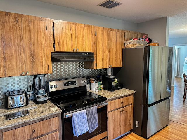 kitchen featuring stainless steel appliances, under cabinet range hood, visible vents, and decorative backsplash