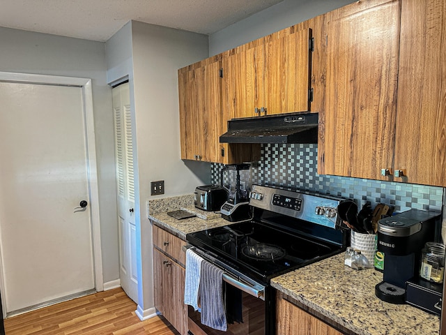 kitchen featuring brown cabinets, stainless steel electric range, light wood-style floors, and under cabinet range hood