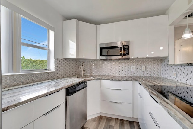 97 Saxony C, Delray Beach, FL 33484 - kitchen with light stone countertops, a sink, white cabinets, stainless steel appliances, and light wood-style flooring