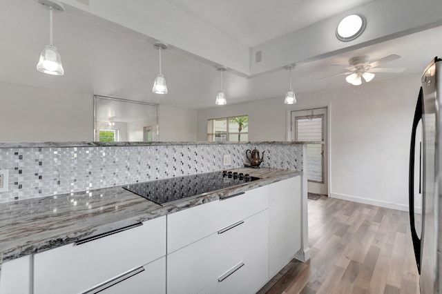 97 Saxony C, Delray Beach, FL 33484 - kitchen with freestanding refrigerator, black electric stovetop, white cabinets, tasteful backsplash, and a ceiling fan