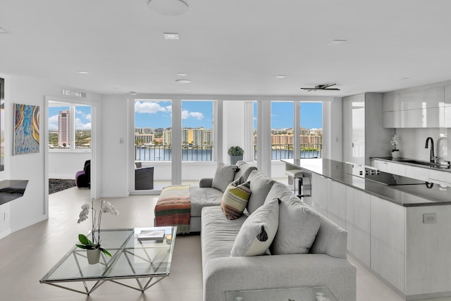 living room with a water view, baseboards, visible vents, and a wealth of natural light