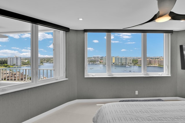bedroom featuring a water view, multiple windows, and a view of city